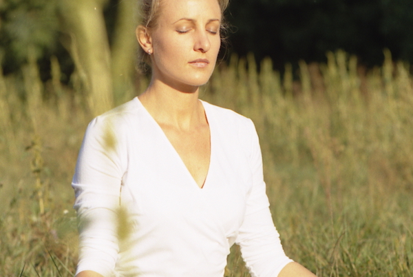 Sabine Barta meditiert, weißes Leibchen gegend die Sonne schauend